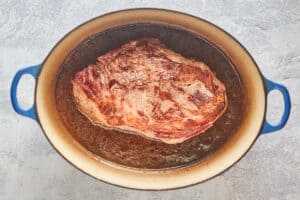browned roast beef and beef stock in a Dutch oven.