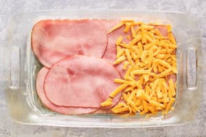 sliced ham and cheese in a baking dish.