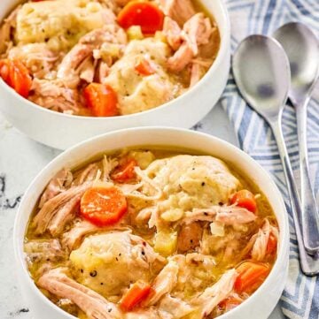 two bowls of homemade chicken and dumplings and two spoons.