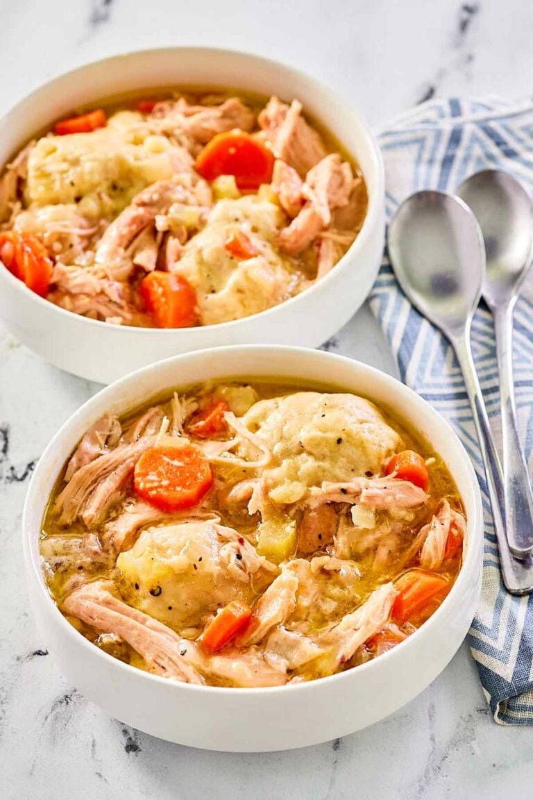 two bowls of homemade chicken and dumplings and two spoons.