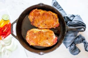 two adobo marinated steaks in a skillet.