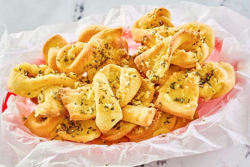 copycat Domino's garlic bread twists on parchment in a basket.