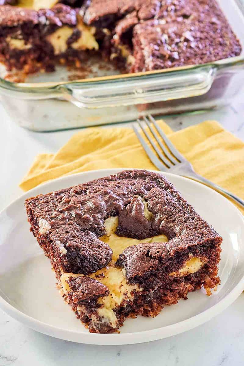 slice of earthquake cake on a plate in front of the cake in a baking dish.