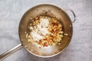 cooked bacon pieces and onions in a skillet.