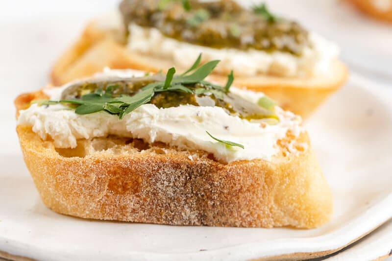 two goat cheese pesto crostini canapes on a plate.