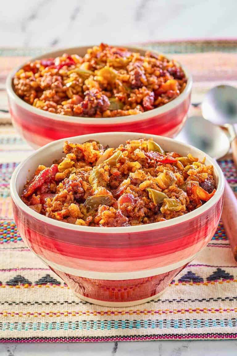 two bowls of Mexican rice casserole and spoons next to them.