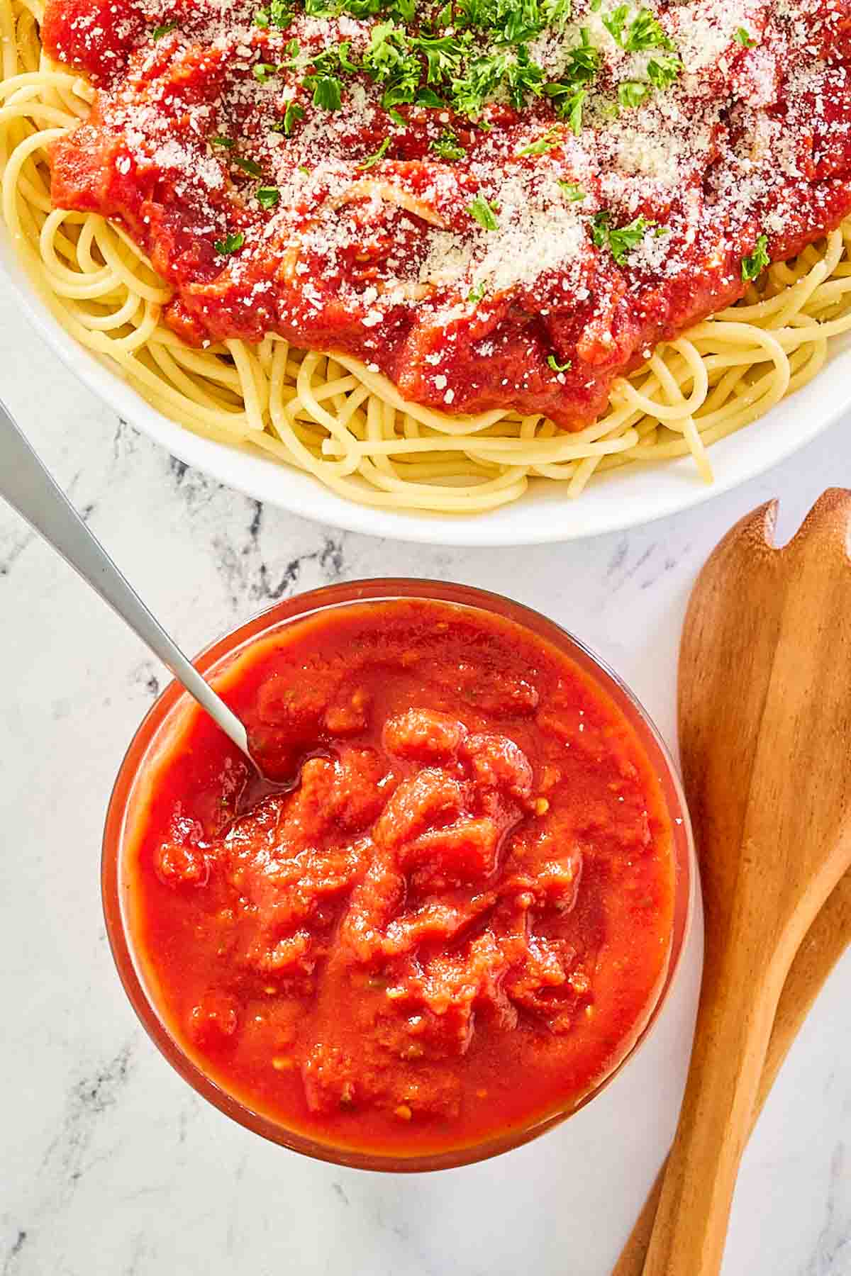 overhead view of copycat Olive Garden marinara sauce in a bowl and over spaghetti.
