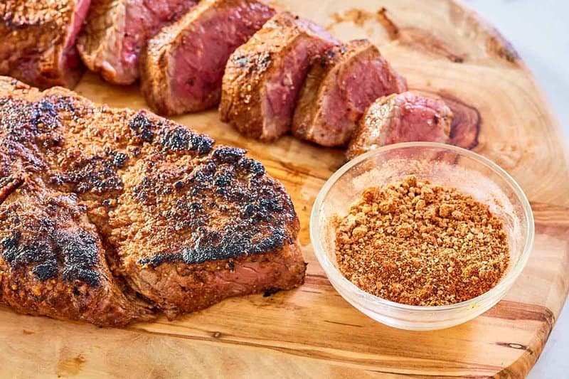 small bowl of copycat Outback steak seasoning next to two steaks.