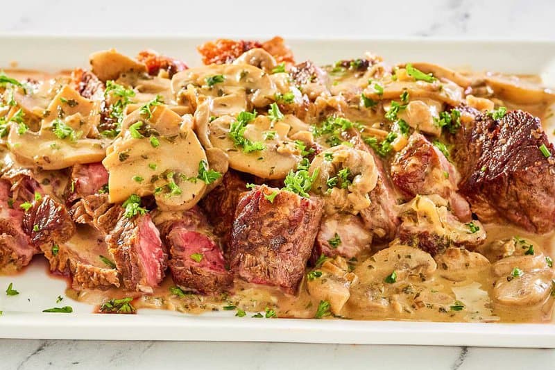 slices of steak marsala with sauce on a platter.