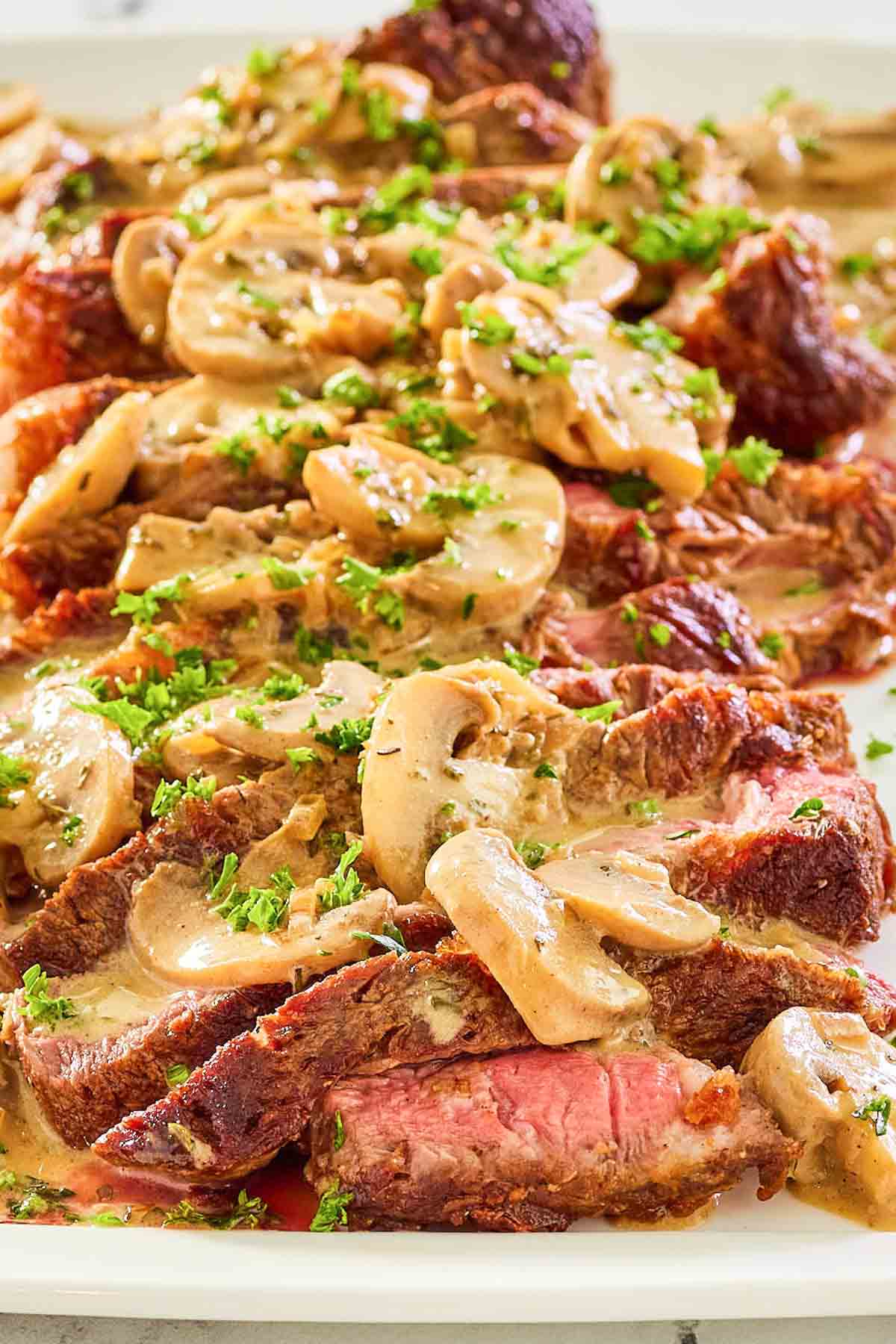 steak marsala with sauce on a white platter.
