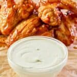 copycat Wingstop ranch in a bowl with chicken wings behind it.