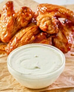 copycat Wingstop ranch in a bowl with chicken wings behind it.