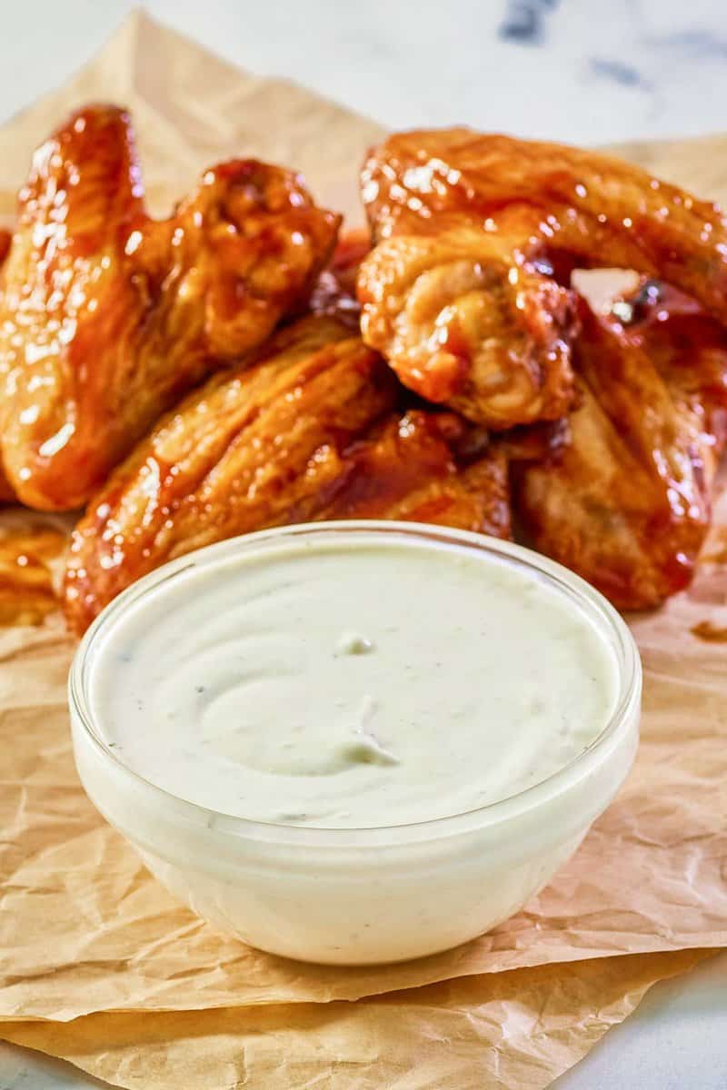copycat Wingstop ranch in a bowl with chicken wings behind it.