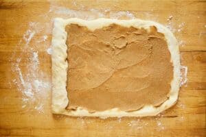 cinnamon roll dough with filling on top and the end rolled up.