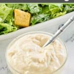 small bowl of creamy caesar dressing with a spoon in it.