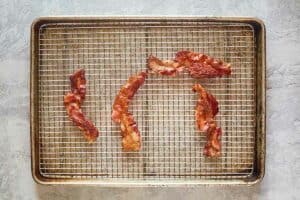 cooked bacon on a wire rack over a baking sheet.