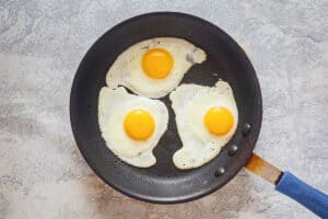 three fried eggs in a skillet.