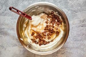 adding chopped Reese's peanut butter cups to pie filling in a bowl.