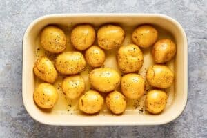 seasoned and oiled baby potatoes in a dish before baking.