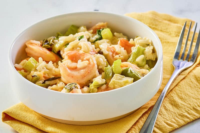 bowl of shrimp casserole, fork, and napkin.