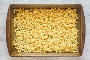 cooked macaroni in the bottom of a baking pan.