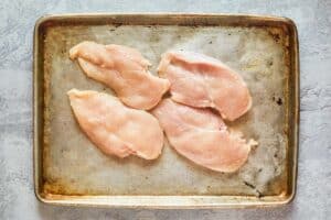 four boneless skinless chicken breasts on a tray.