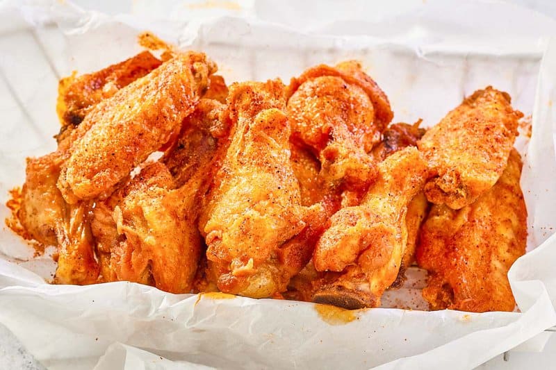 copycat Wingstop Cajun chicken wings in a wire basket lined with parchment.