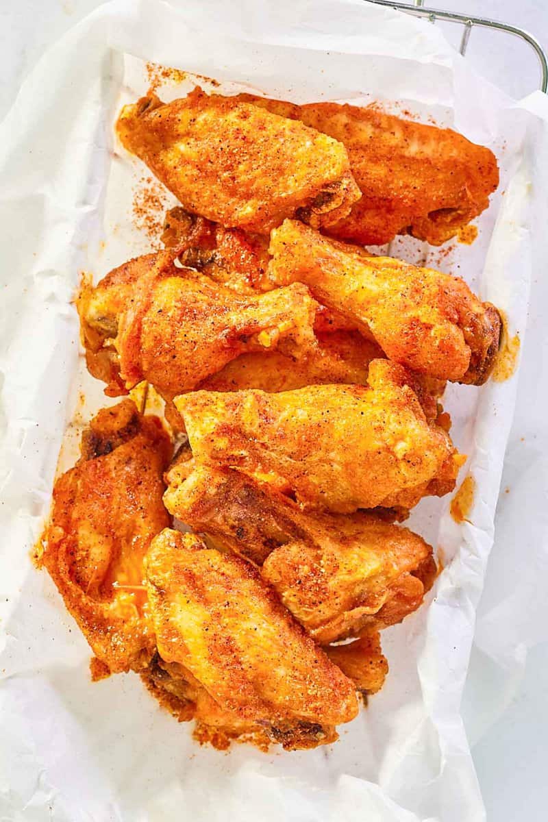 overhead view of Wingstop cajun wings in a parchment paper lined wire basket.