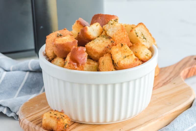 A bowl of air fryer croutons in front of an air fryer.
