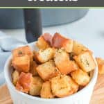 Air fryer croutons in a bowl in front of an air fryer.