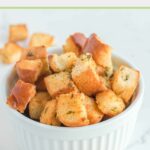 Air fryer croutons in and beside a white bowl.