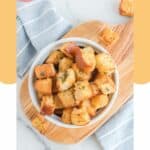 Overhead view of air fry croutons in a bowl on top of a wood cutting board.
