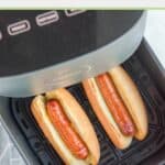 Two hot dogs in buns in an air fryer.