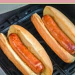 Closeup of two air fried hot dogs in buns in an air fryer basket.