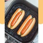 Two hot dogs in buns in an air fryer basket.