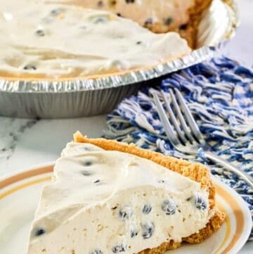 blueberry cream pie slice on a plate and the pie behind it.