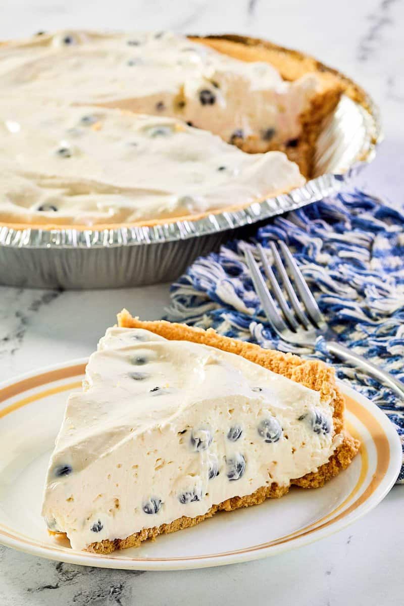 blueberry cream pie slice on a plate and the pie behind it.