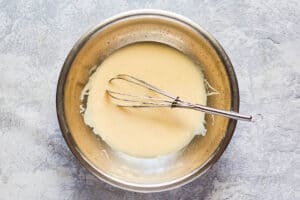 sweetened condensed milk, lemon juice, and a whisk in a mixing bowl.