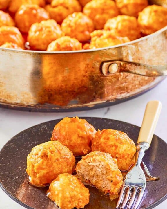 Buffalo chicken meatballs on a plate and in a pan.