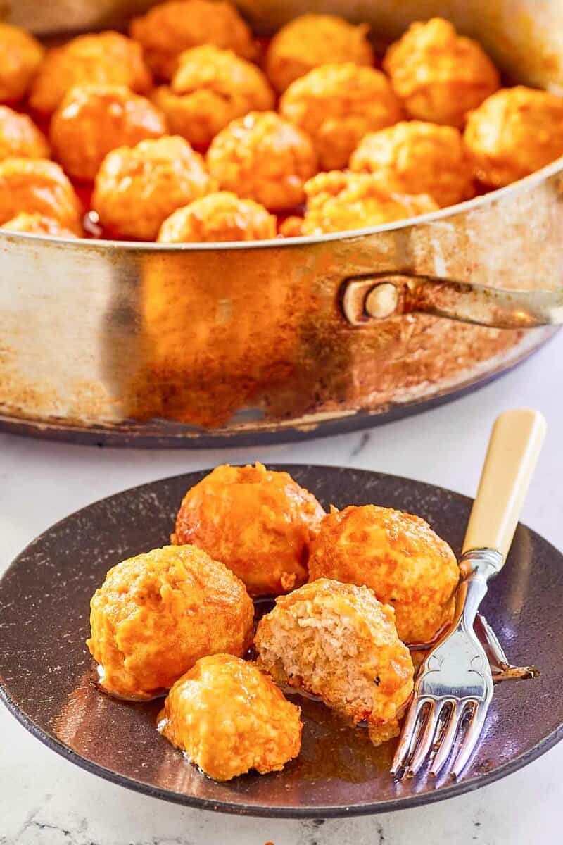 Buffalo chicken meatballs on a plate and in a pan.