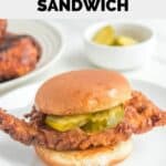 Homemade Chick Fil A spicy chicken sandwich and a bowl of pickle slices.