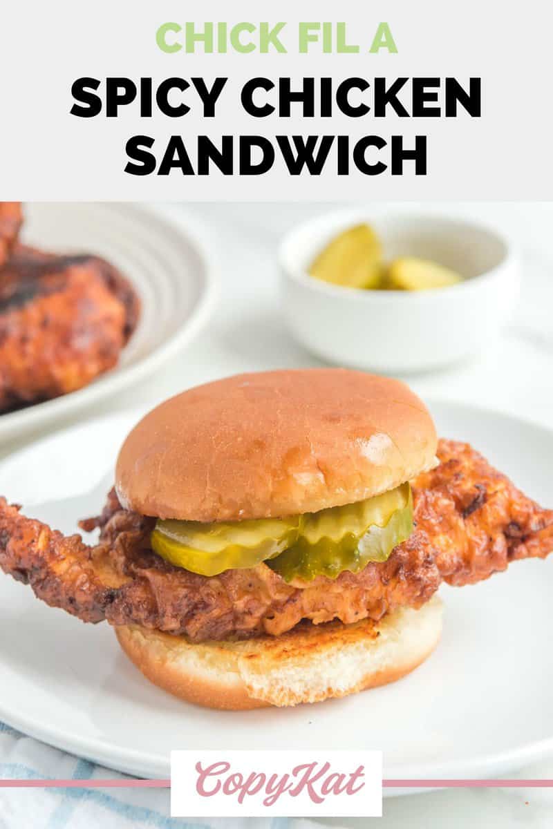 Homemade Chick Fil A spicy chicken sandwich and a bowl of pickle slices.