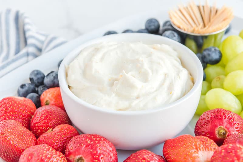 Cream cheese fruit dip on a platter with fresh fruit and toothpicks.