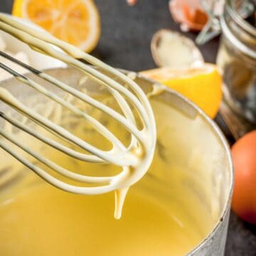 homemade hollandaise sauce in a pan and on a whisk.