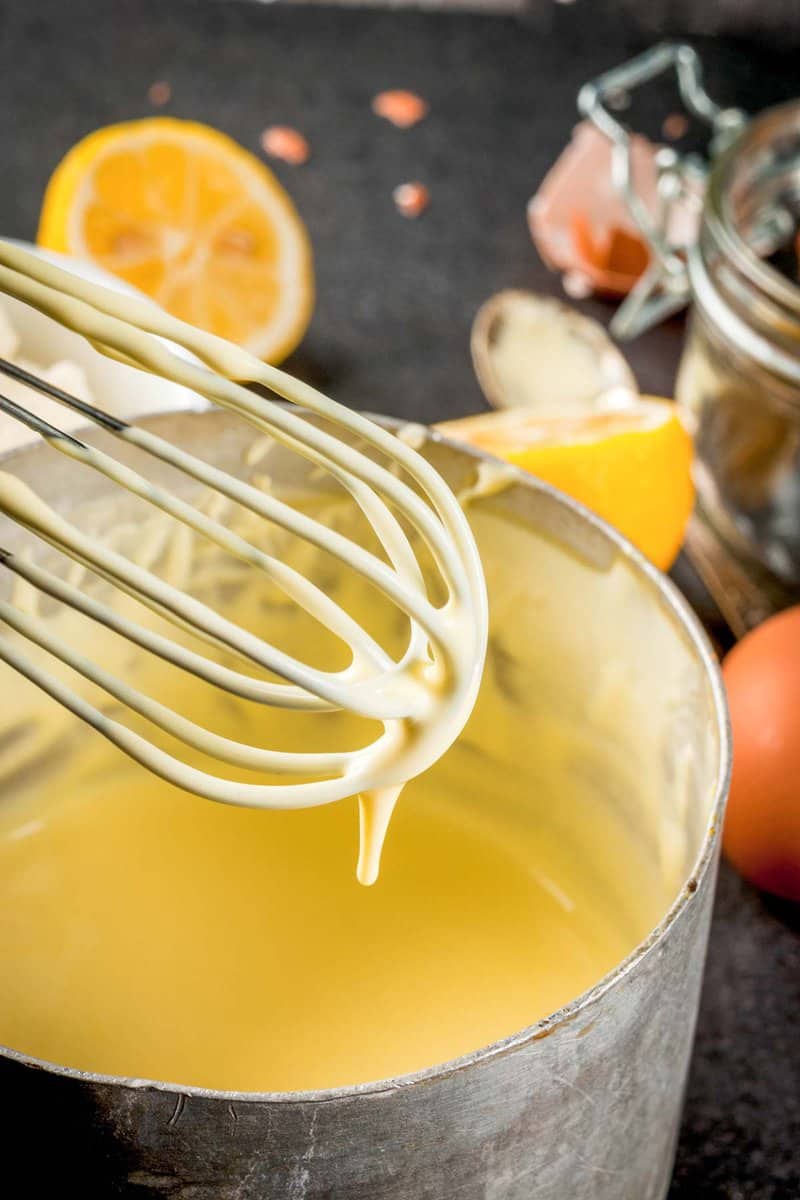 homemade hollandaise sauce in a pan and on a whisk.