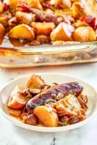 Irish coddle serving on a white plate in front of it in a baking dish.