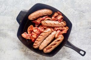 cooked sausages and bacon in a cast iron grill pan.
