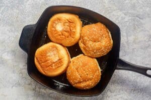 four hamburger buns in a skillet.