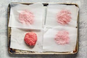 ground beef patties on a baking sheet.