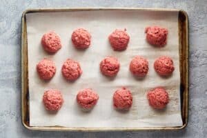 Uncooked meatballs on a baking sheet..